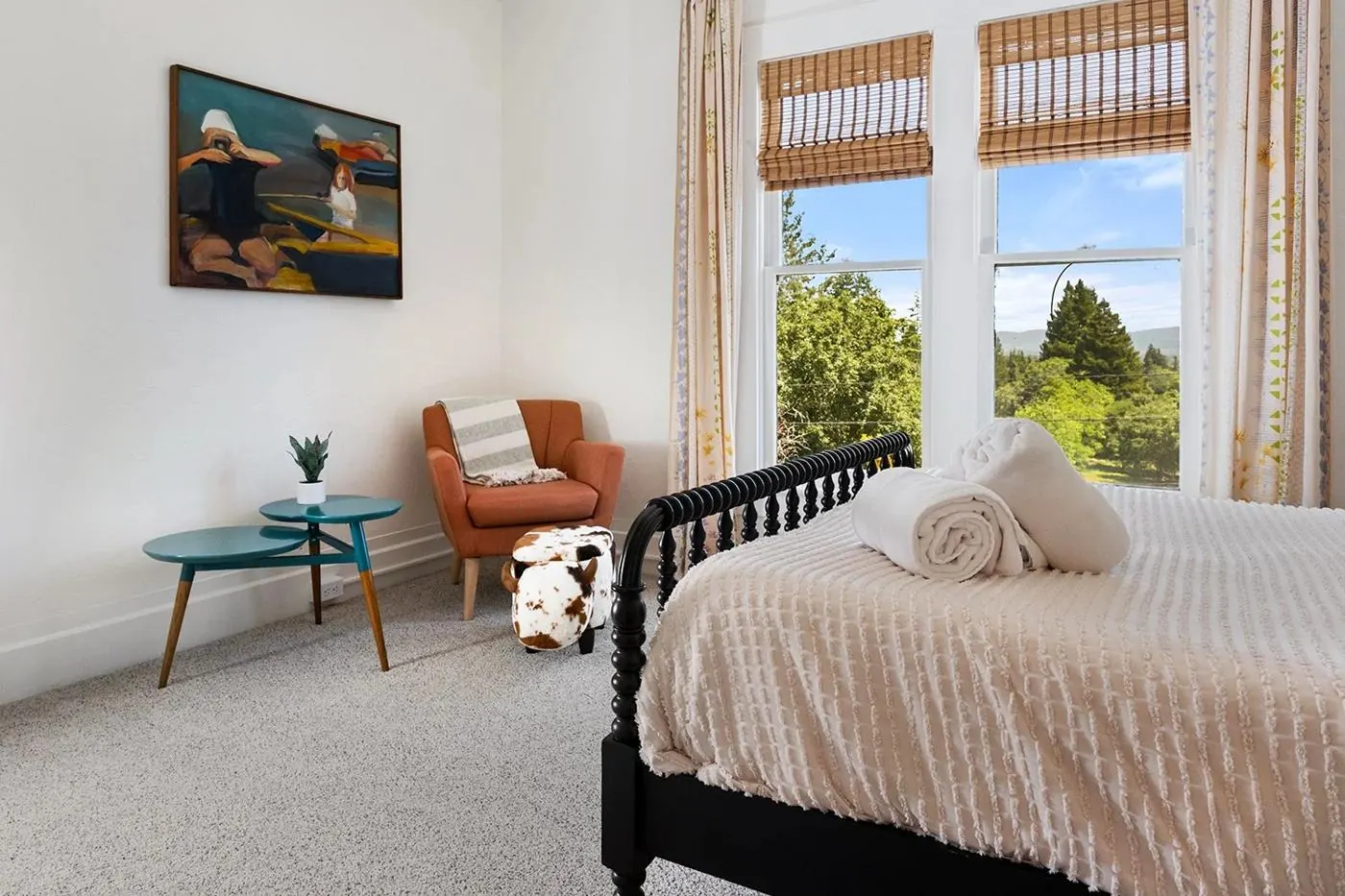 Bedroom with spindle bed, orange armchair and valley views