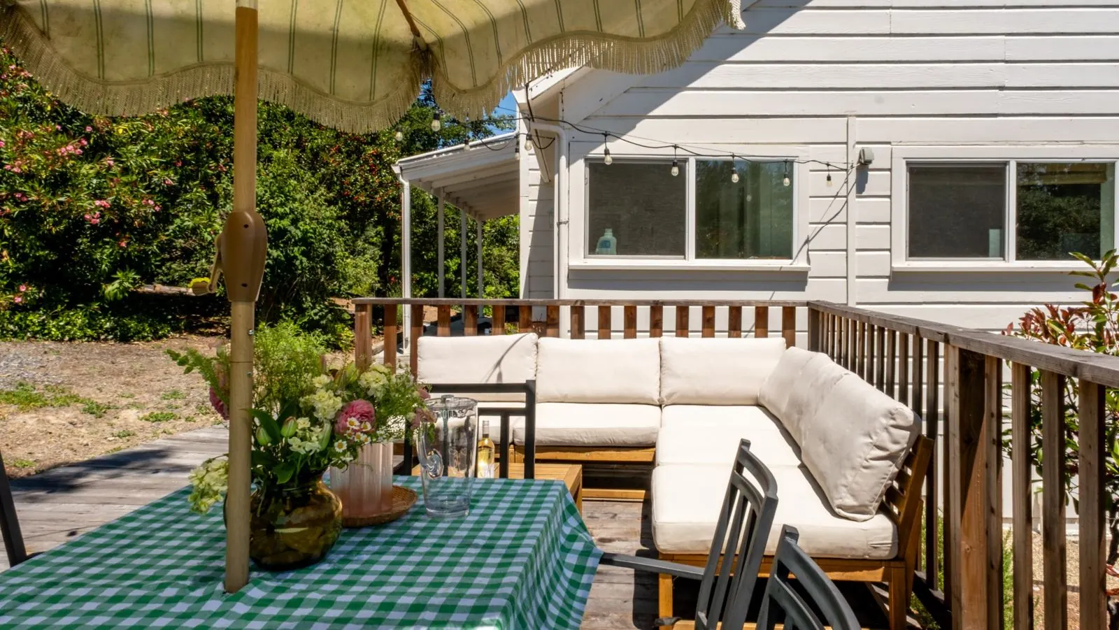 Outdoor sectional sofa and gingham-covered dining table beside the farmhouse