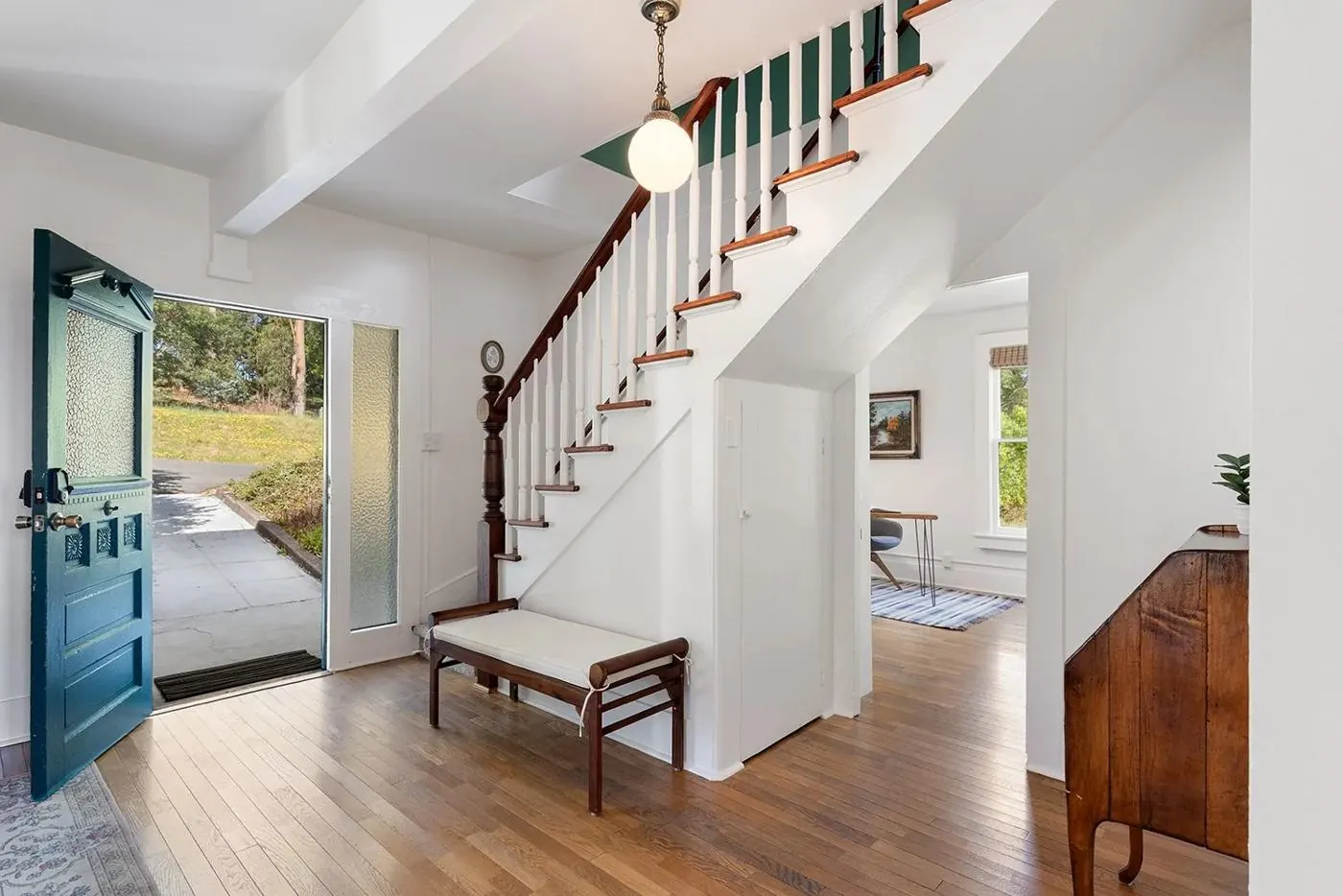 Entry hall with original oak floors, turned-spindle staircase and green front door