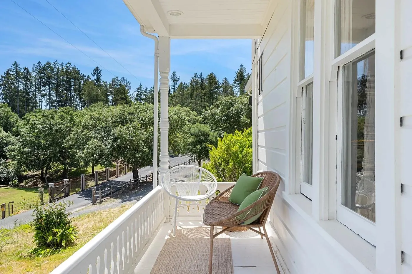 Covered porch with wicker chairs overlooking the trees